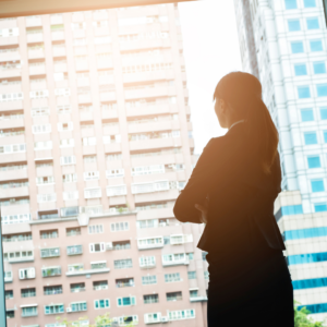 Overwhelmed woman looking out her office window at the city